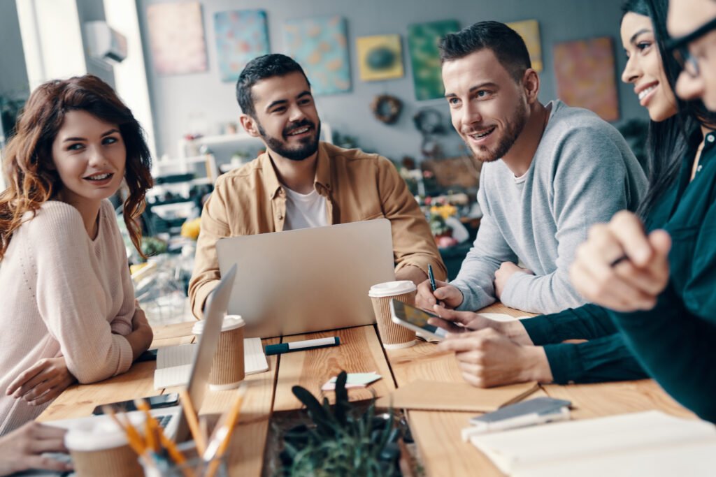 collaboration. group of young modern people in smart casual wear discussing something and smiling while working in the creative office